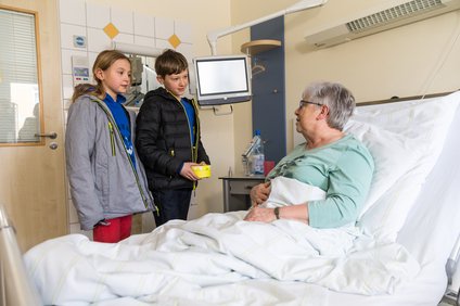 Frau im Krankenhaus wird von 2 Kindern besucht