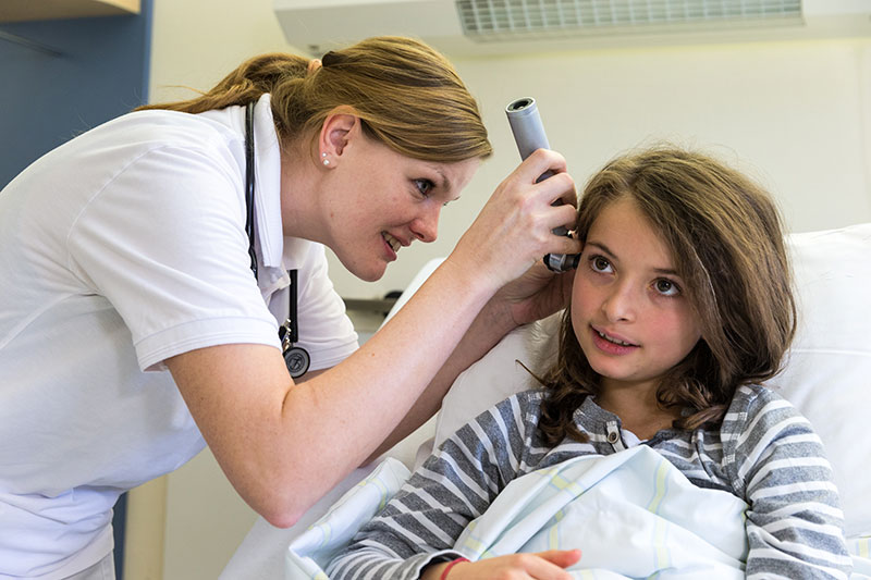 Ärztin untersucht Ohr eines Kindes