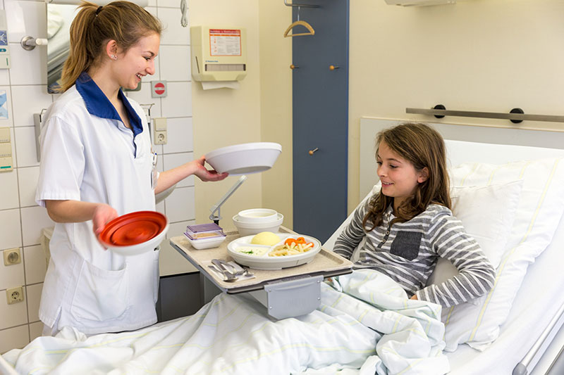 Pflegerin mit Essen am Bett