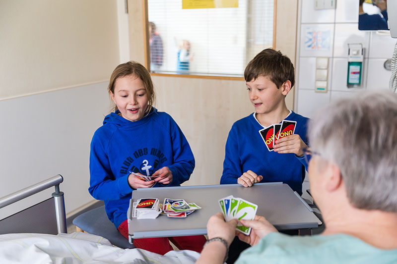 Frau spielt mit Kindern Karten